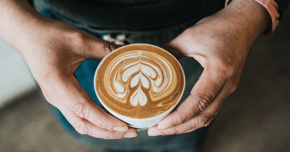 Hands holding latte with latte art with hearts