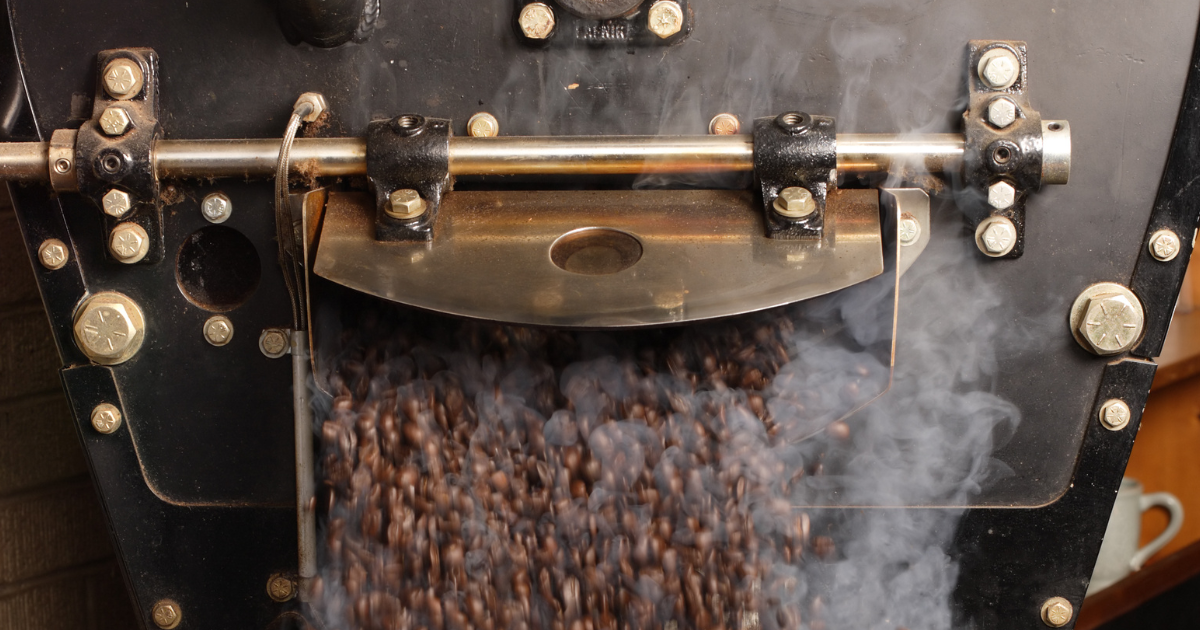 Freshly roasted coffee coming out of a roaster with steam rising