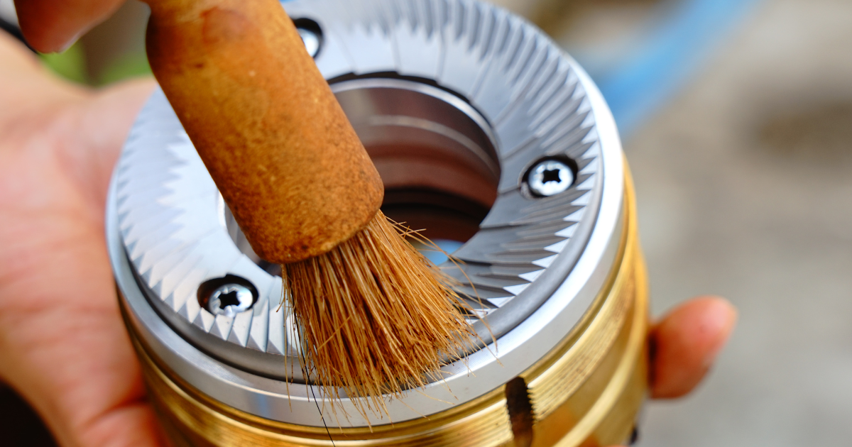 Cleaning burr coffee grinder | Img by Supersmario from Getty Images Signature - Genuine Origin Coffee Cleaning burr coffee grinder with a brush to properly maintain.