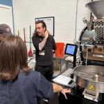Keenan Burages from Intelligentsia explaining a coffee roasting machine to a small group in a workshop setting