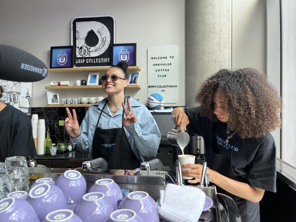 Kayla McBride in a barista uniform learning how to make coffee