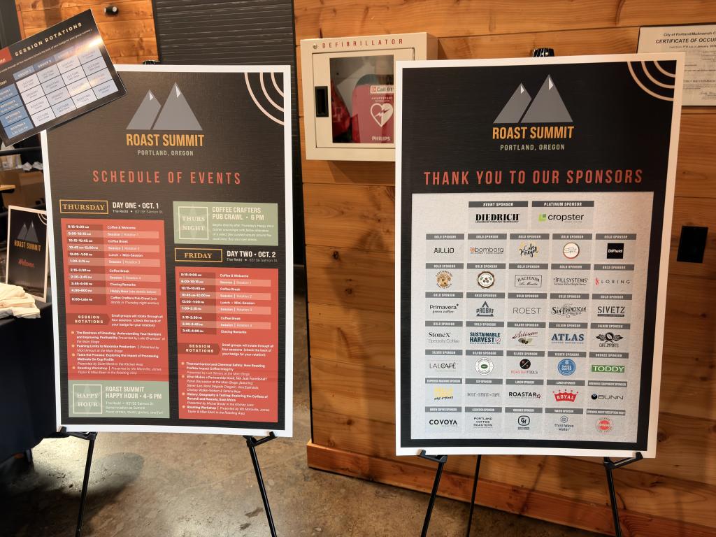 Two signs displaying the schedule of events for Roast Summit Portland in front of a wooden wall